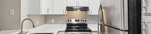 a kitchen with white cabinets and stainless steel appliances
